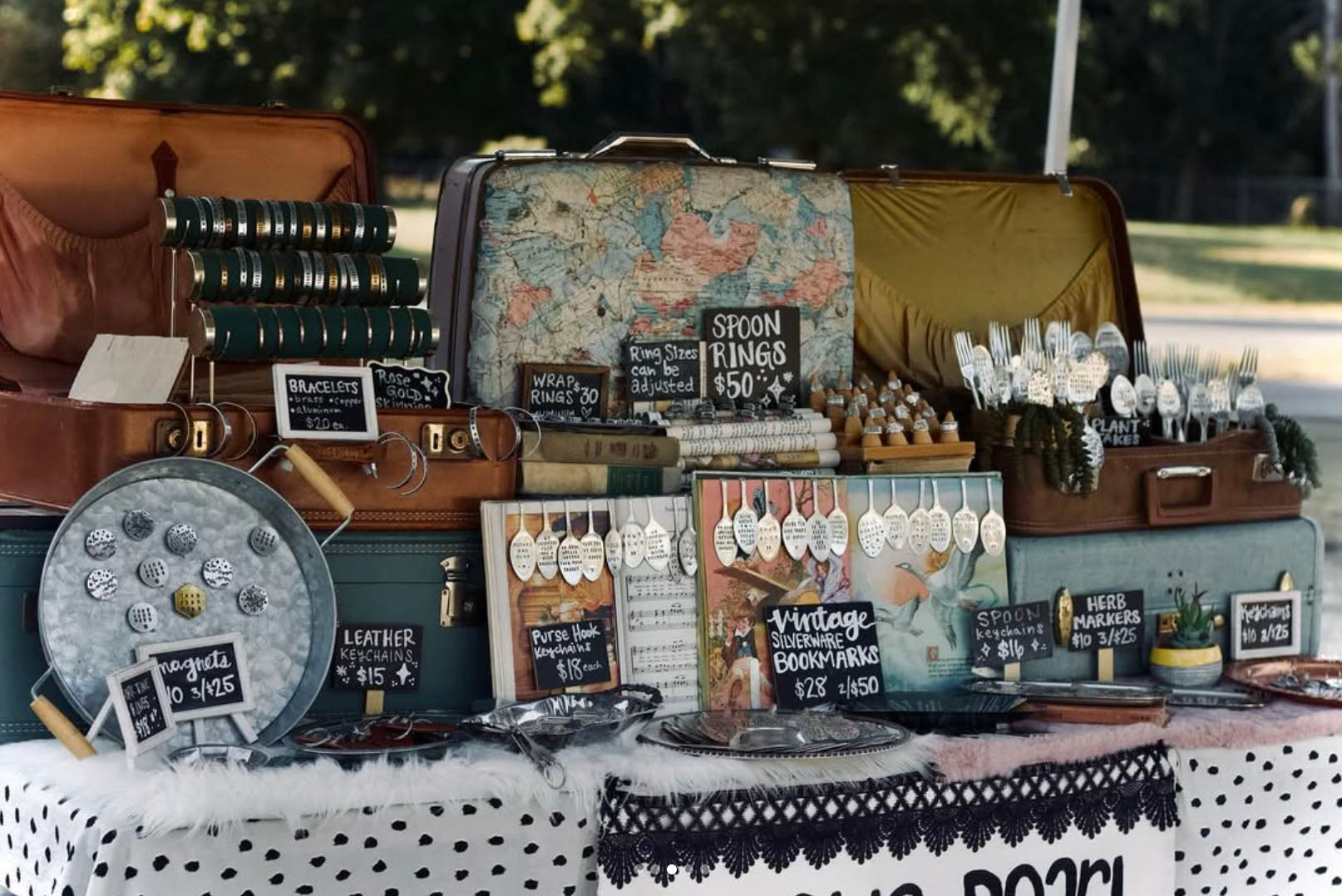 Vintage-themed table display with suitcases, maps, and decorative items on a polka dot tablecloth.